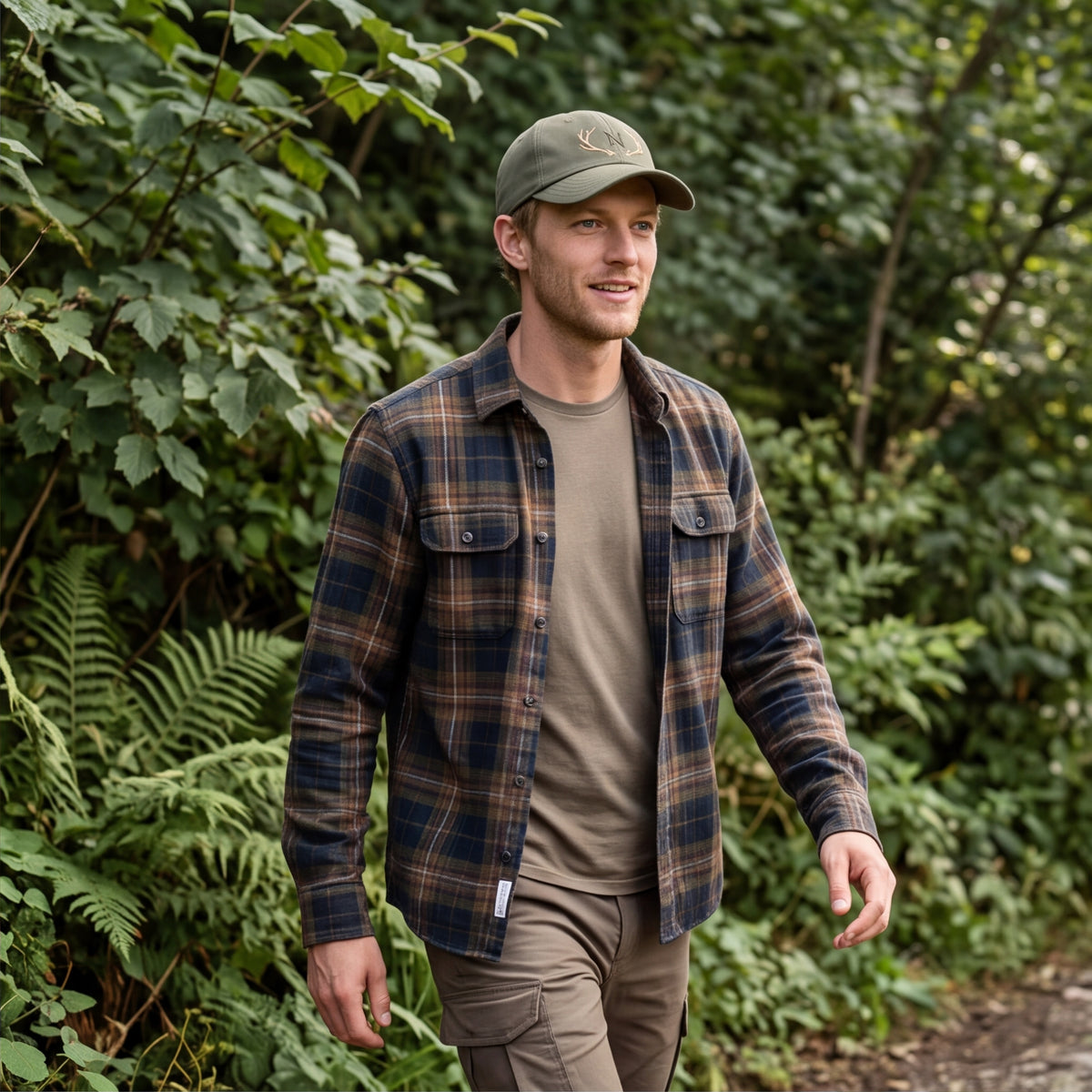 Mann im Karohemd trägt die olivengrüne personalisierte Geweih-Cap bei einem Spaziergang im Wald.
