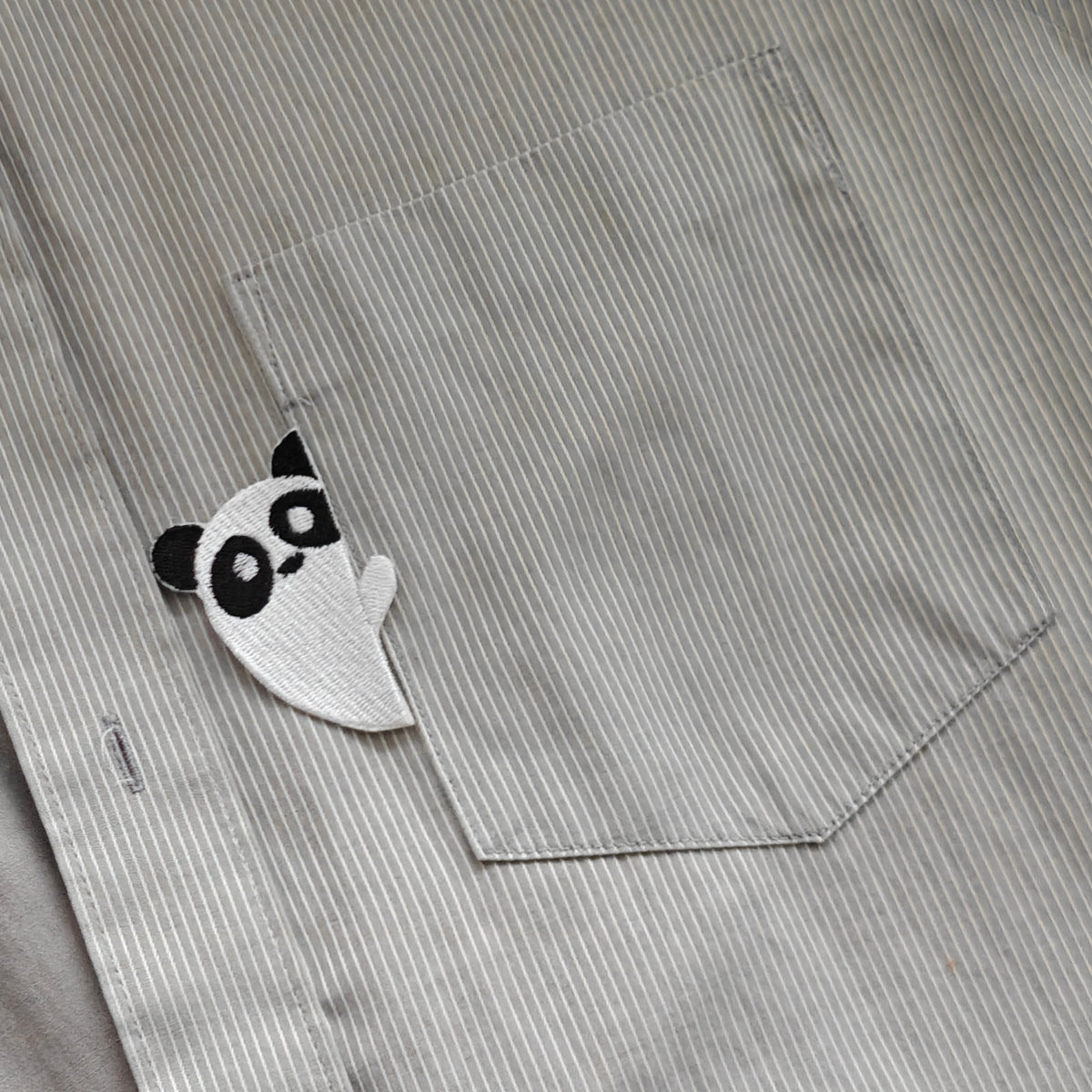 Besticktes Panda-Bügelbild, platziert an der Ecke einer Hemdtasche als kreative Kleider-Applikation.