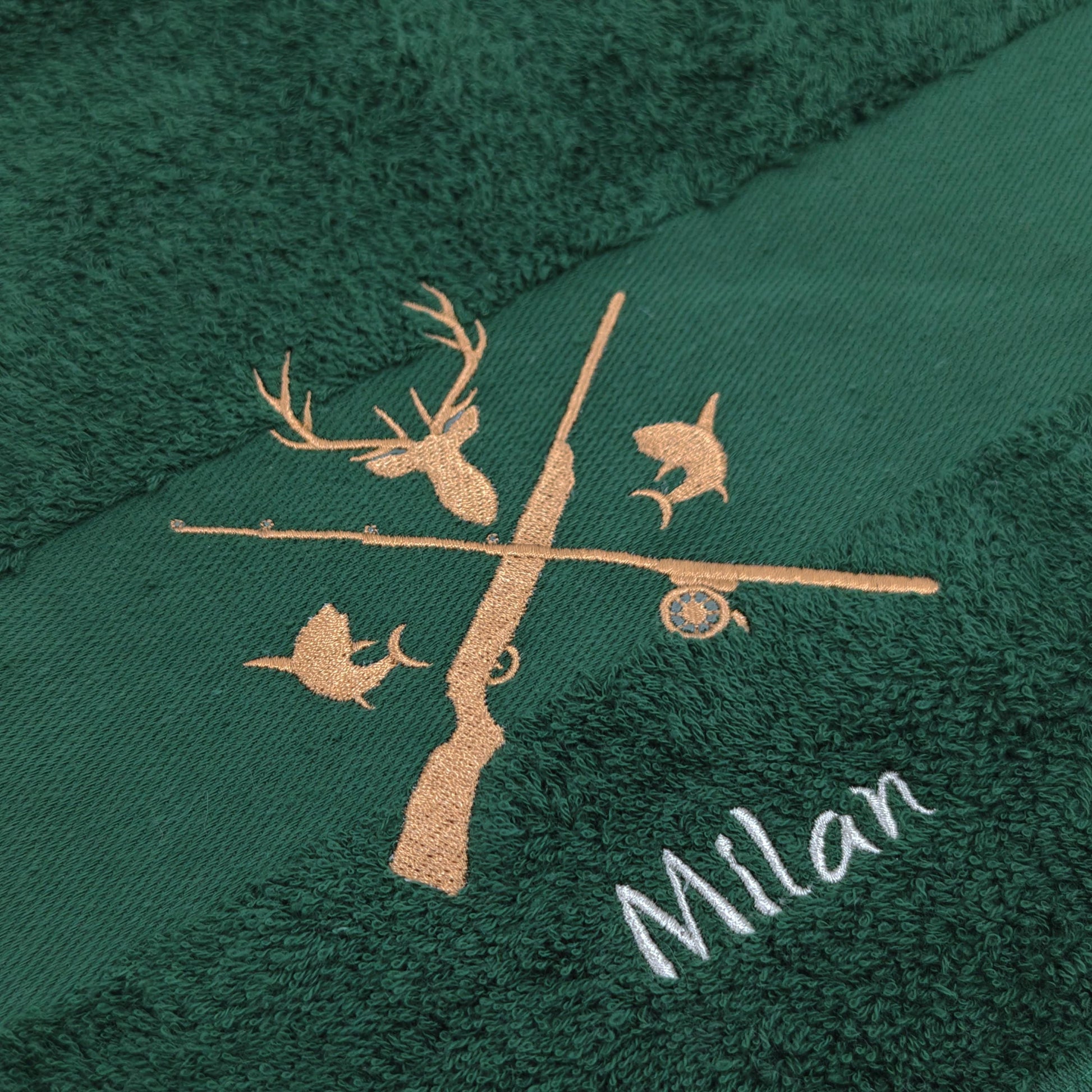 Nahaufnahme der Jagd und Angeln Motiv mit Namen Stickerei um die Qualität zu zeigen. Die Stickerei ist auf einem dunkelgrünen Handtuch angefertigt.